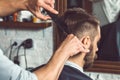 The hands of young barber making haircut to attractive man in barbershop Royalty Free Stock Photo