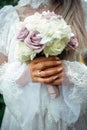 Hands of young bride holding beautiful wedding bouquet. Bride`s hand with a wedding ring on her finger. Bride in vintage white Royalty Free Stock Photo