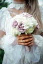 Hands of young bride holding beautiful wedding bouquet. Bride`s hand with a wedding ring on her finger. Bride in vintage white Royalty Free Stock Photo