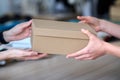 Hands of young craftswoman passing packed box with leatherwear to buyer Royalty Free Stock Photo