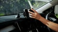 Hands of a young European girl sitting in a car with a black interior, inserts a smartphone into the phone mount on the front to Royalty Free Stock Photo