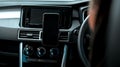 Hands of a young European girl sitting in a car with a black interior, inserts a smartphone into the phone mount on the front to Royalty Free Stock Photo