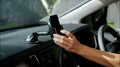 Hands of a young European girl sitting in a car with a black interior, inserts a smartphone into the phone mount on the front to Royalty Free Stock Photo