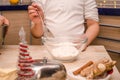 Hands of young girl prepare festive Christmas gingerbread cookies for christmas, she pours flour on dough