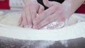 Hands of young man knead the edges of the dough close up