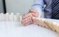 Hands of the young man prevent Dominoes from falling to reduce business risks Royalty Free Stock Photo