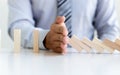 Hands of the young man prevent Dominoes from falling to reduce business risks