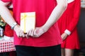Hands of man wear red t-shirts holding gold gift box behind his back surprise for girlfriend. New year concept Royalty Free Stock Photo