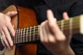 The hands of a young musician playing an acoustic guitar with metal strings close-up with a blurred background Royalty Free Stock Photo