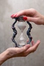 Hands of a young and old woman holding an hourglass