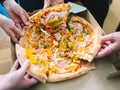 Hands of young people taking pizza slices from delivery cardboard box dining together, friends sharing meal having lunch at home Royalty Free Stock Photo