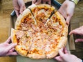 Hands of young people taking pizza slices from delivery cardboard box dining together, friends sharing meal having lunch at home Royalty Free Stock Photo