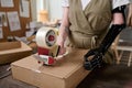 Hands of young warehouse worker with myoelectric arm sealing box with cellotape Royalty Free Stock Photo