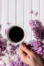 coffee mug in hand.Hands of young woman drinking coffee on white wooden table with flowers, gift. Woman hand hold cup of Royalty Free Stock Photo