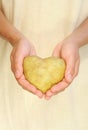 Hands of young woman holding potato in heart shape