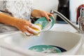 Hands young woman washing dirty dishes in kitchen sink with washcloth and detergent Royalty Free Stock Photo