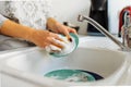 Hands young woman washing dirty dishes in kitchen sink with washcloth and detergent Royalty Free Stock Photo