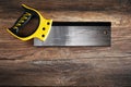 Handsaw with plastic yellow handle on vintage wooden table under dark dramatic moody lighting Royalty Free Stock Photo