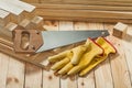 Handsaw and yellow working gloves on wooden timber materials Royalty Free Stock Photo