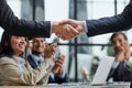 Handshake in agreement against young business people in board room meeting Royalty Free Stock Photo