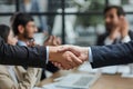 Handshake in agreement against young business people in board room meeting Royalty Free Stock Photo