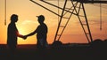 handshake agriculture. silhouette two farmers sign a contract shake hands on the background of an irrigation machine in