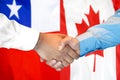 Handshake on Chile and Canada flag background