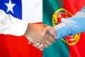Handshake on Chile and Portugal flag background