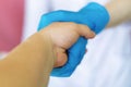 Handshake with the Doctor. The doctor`s hand in a blue latex glove holds the patient`s hand in close-up. Shake hands. The concept Royalty Free Stock Photo