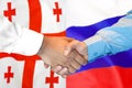 Handshake on Georgia and Russia flag background