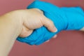 Handshake, gratitude, care, trust, protection, care and support. The doctor`s hand in a blue rubber glove holds the patient`s hand