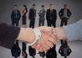 Handshake with handcuffs in front of business people in grey room Royalty Free Stock Photo