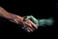 Handshake of human hand on one side and alien creature with green skin on other hand