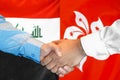 Handshake on Iraq and Hong Kong flag background. Men handshake on the background of the Iraq and Hong Kong flag. Support concept Royalty Free Stock Photo