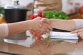 Handshake in the kitchen, closeup. Two women agreed about menu. Cooking and friendship concept. Royalty Free Stock Photo