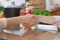 Handshake in the kitchen, closeup. Two women agreed about menu. Cooking and friendship concept. Royalty Free Stock Photo