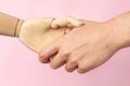 Handshake of man and robot wooden hand on pink background