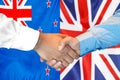 Handshake on New Zealand and UK flag background