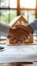 Handshake Over Architectural Plans and Model House Royalty Free Stock Photo