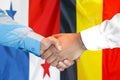 Handshake on Panama and Belgium flag background