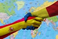 Handshake between Spain and Romania flags painted on hands.
