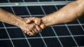 Handshake of two businessmen on a background surface of solar panels