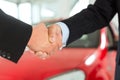 Handshake of two men in suits with a red car