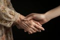 Handshake of two women, young and old, close-up. The hand of a young girl holds the hand of an elderly woman. Two hands, two Royalty Free Stock Photo