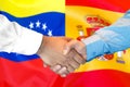 Handshake on Venezuela and Spain flag background