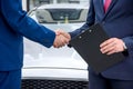 Handshakes of two men against hood of a car