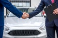 Handshakes of two men against hood of a car