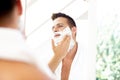 Handsom man standing in front of bathroom mirror while shaving Royalty Free Stock Photo