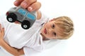 Handsome adorable fair hair boy showing a wooden car toy and making a special facial attitude Royalty Free Stock Photo