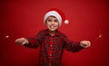 Handsome adorable preteen boy, beautiful child in Santa Claus hat and checkered shirt enjoys the Christmas party, plays with